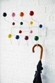 Umbrella hanging from coat rack with colourful balls on hooks