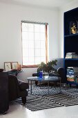 Armchairs, round glass table, shelving unit & striped rugs in living room