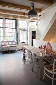 Dining area with plastic shell chairs at wooden table; rustic bench below lattice window in background