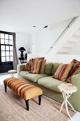 Ottoman with striped cover and wooden side table in front of comfortable sofa in living room