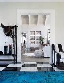 View from foyer with glossy chequered, tiled floor and blue rug into open-plan, country-house-style living area