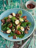 Spinach salad with quail's eggs poached in tea, and bacon
