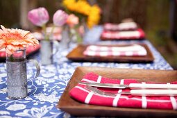 Gedeckter Tisch mit braunen Tellern und Blumen im Freien