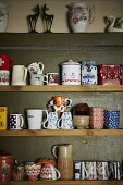 Einfaches Holzregal mit gesammelten Kaffetassen, Teeschalen und Porzellandosen