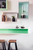 Decorative, wall-mounted shelving units above long shelf used as counter and bar stools