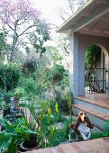 Veranda mit Ziegelsteinboden mit angrenzendem sommerlichem Garten und springendem Hund