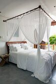 Four-poster bed with white bed linen in white bedroom