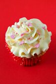 A cupcake with buttercream icing and sugar hearts for Valentine's Day