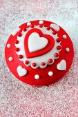 Cupcake mit rot-weisser Glasur und Herzen