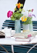 Garden flowers in various vases and books on delicate metal table