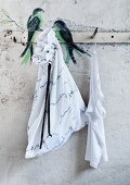 Hakenleiste mit aufgemalten Vögeln und mit Gedichttext beschriftetem, schlichtem, weißem Wäschesack