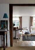 Konsolentisch mit zierlicher Tischleuchte neben breitem Durchgang und Blick ins Wohnzimmer auf Rokoko Schemel und Sesseln