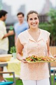 Frau hält Tablett mit Grillgut & Salat