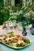 Sommersalat mit Tomaten und hartgekochten Eiern auf Gartentisch (Schweden)