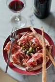 Parma ham with capers, grissini and red wine