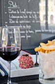 Beef tartar, crisps and a glass of red wine in a bistro