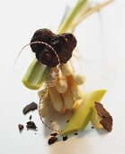 A still life of ingredients featuring white asparagus, truffles and leek