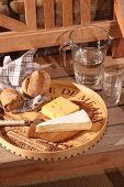 Selbst gefertigtes Käsebrett aus altem Weinkisten mit Spanholzrand; Wasserkaraffe und Gläser auf Holzbank