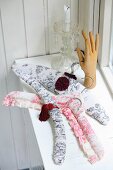 Coat hangers with handmade covers in toile de jouy fabric and sculpture of hand in front of candlestick on windowsill