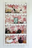 Tellerregal mit rot-weisser Toile-de-Jouy Tapete auf Rückwand