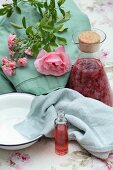 Homemade rose vinegar in a small vial with a carafe of rose petals steeped in vinegar behind it