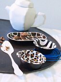 Various bowls painted with different animal-skin patterns arranged on black tray