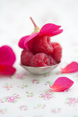 Raspberries on a silver spoon with geranium blossoms