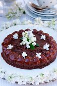 Chocolate cake with white lilac blossoms on a garden table
