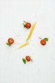 A clock face made from tomatoes, basil and spaghetti