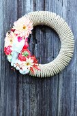 Love-themed decorative wreath made of coiled rope and flowers on wooden wall