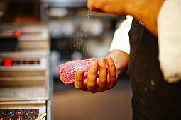 Koch würzt Rindersteak mit Salz
