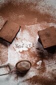 Three brownies dusted with cocoa on a scrap of white paper with the word Enjoy