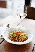 Penne with tomatoes and courgette, with a glass of white wine