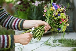 Florist's hands trimming stems of summer bouquet