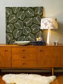 Panel of floral fabric, table lamps and books on fifties sideboard