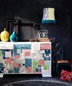Colourful sideboard with patchwork motifs in front of wall painted with blackboard paint