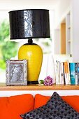 Table lamp with black shade and yellow base on partition wall