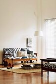 Coffee table improvised from table top on stacks of magazines in front of upholstered bench in black and white ethnic pattern