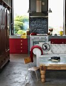 Open-plan interior of architect-designed house with red kitchen cupboards, screed floor and tall windows