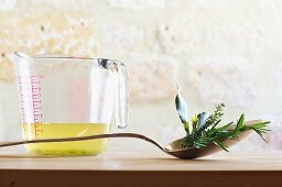 A still life featuring clear vegetable stock and fresh herbs