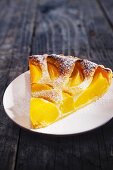 A slice of peach tart with icing sugar