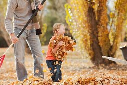 Vater und Tochter rechen die Herbstblätter zusammen
