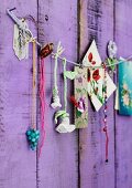 Gehäkelte Blume, Perlenschmuck und Bilder mit Blumenmotiven an Kordel mit Wäscheklammern aufgereiht
