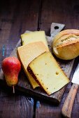 Various types of cheese from Germany with a pear and a bread roll