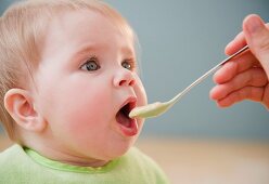 Mother feeding Caucasian baby