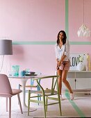Various pastel chairs around Tulip Table and woman in front of pink wall with green stripes