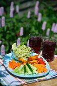 Guacamole und Gemüsesticks auf Gartentisch