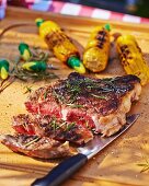 Grilled beef steak with corn on the cob on a garden table