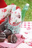 Chocolate muffins on checked tea towel and partially visible cloth picnic bag with floral pattern