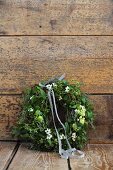 Romantic Christmas wreath of mistletoe and Star-of-Bethlehem flowers leaning against wooden wall